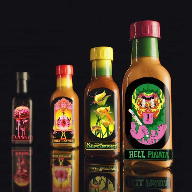 Four hot sauce bottles with illustrated labels sit in a row, reflecting on a glossy black surface against a dark background.