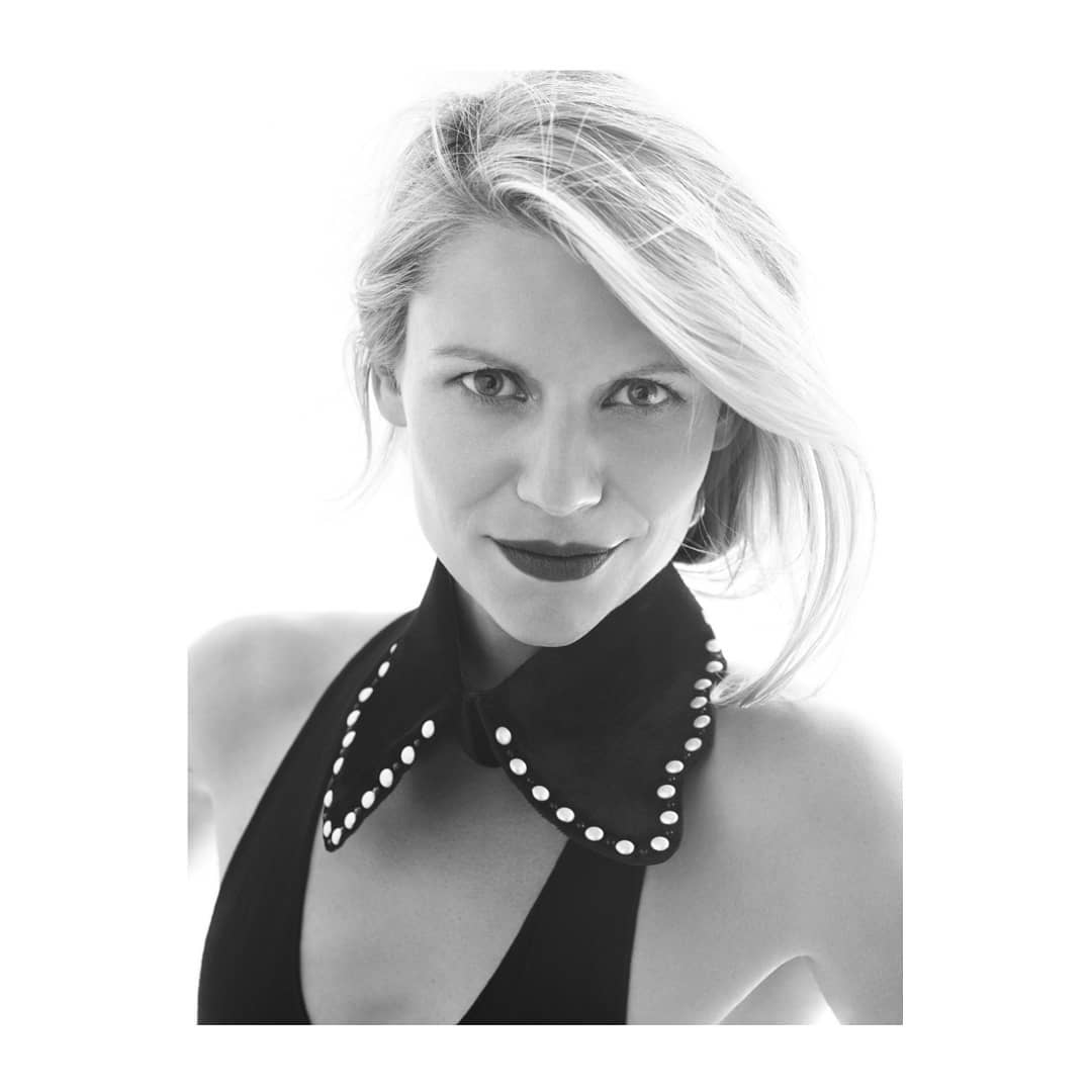 Black and white portrait of a fair-skinned woman with blonde hair, dark red lipstick, and wearing a black dress with white beaded collar.