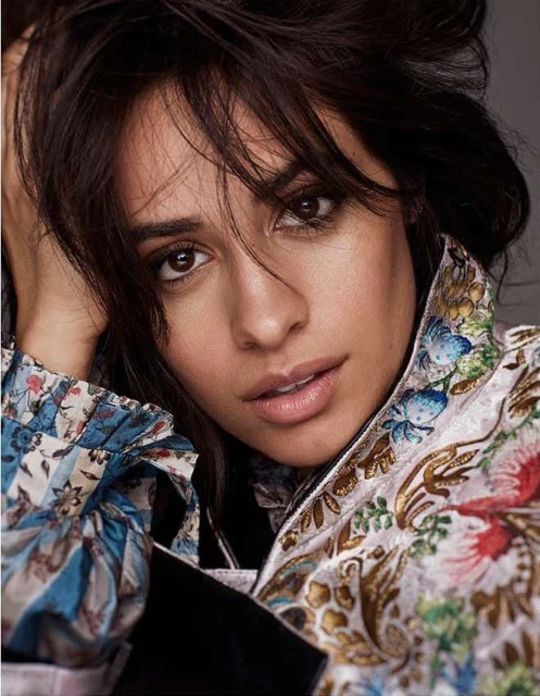 Close-up portrait of a woman with dark hair, wearing a floral print jacket. She is gazing directly at the camera in a photo studio.