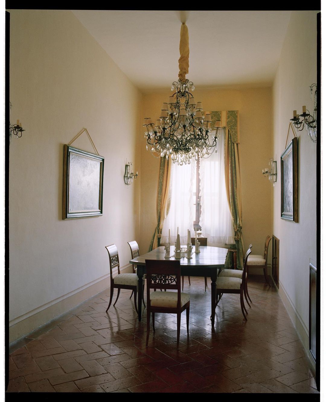 Elegant dining room interior featuring a formal dining table set with candles, surrounded by ornate chairs, and lit by a chandelier.