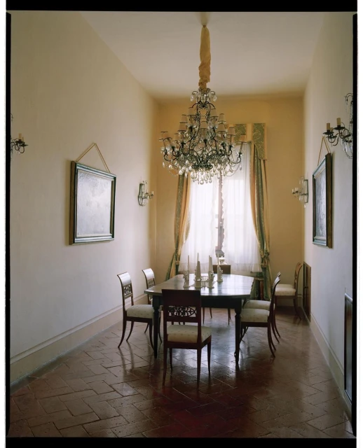 Elegant dining room interior featuring a formal dining table set with candles, surrounded by ornate chairs, and lit by a chandelier.