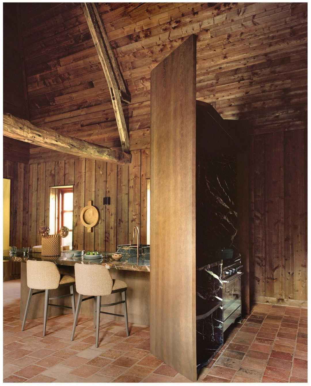 Rustic kitchen interior with wooden walls and ceiling, marble countertops, and stylish seating, creating a warm and inviting space.