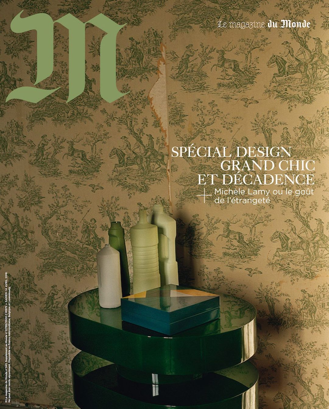 Magazine cover featuring decorative wallpaper backdrop, a round green table with sculptural objects and a rectangular box on top.