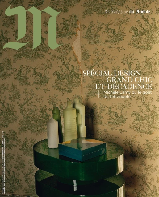 Magazine cover featuring decorative wallpaper backdrop, a round green table with sculptural objects and a rectangular box on top.