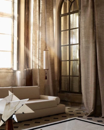 Interior view of an elegant room in Paris with tall arched windows, sheer curtains, a low sofa, and a sculptural lamp by Alexis Armanet