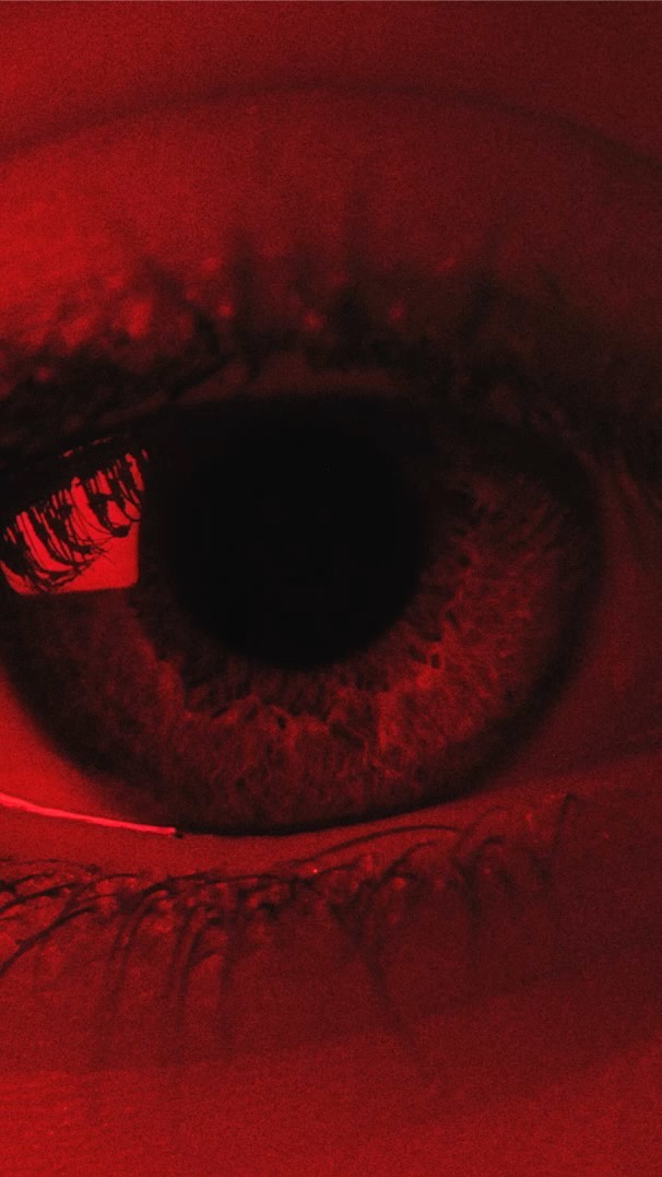 Close-up shot of an eye featuring striking red color grading, enhancing its texture and details, creating a visually intense effect.