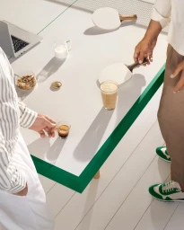 High angle shot of two men standing by a white table holding ping pong paddles, espresso cup, laptop, and drinks in Paris by Alice Cuvelier