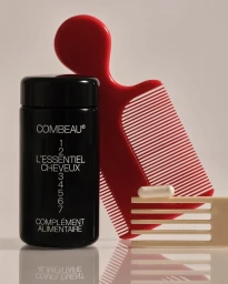 Black supplement bottle beside a bright red comb and a pale beige comb holding a single white capsule