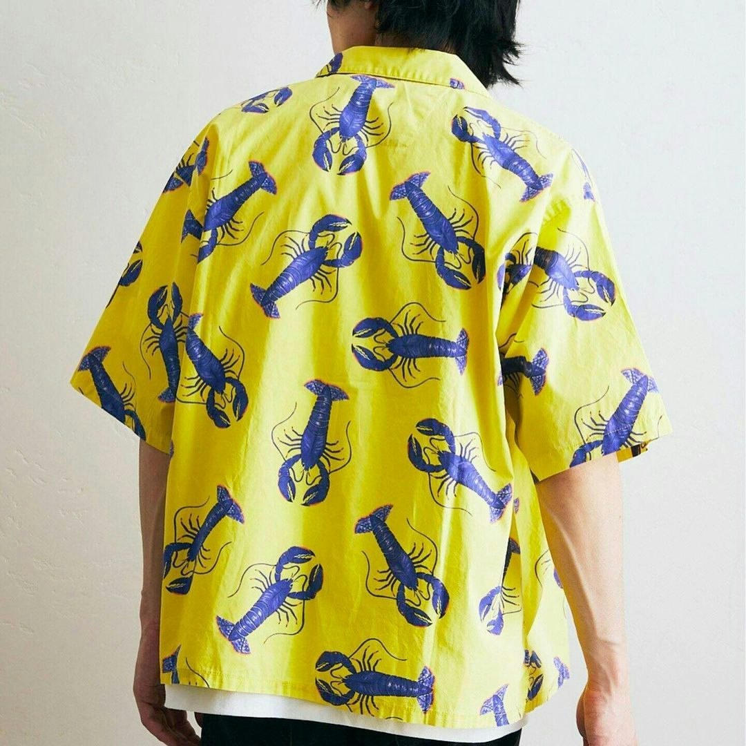 Back view of a person wearing a short-sleeved button-down shirt patterned with repeating blue lobsters against a yellow background.