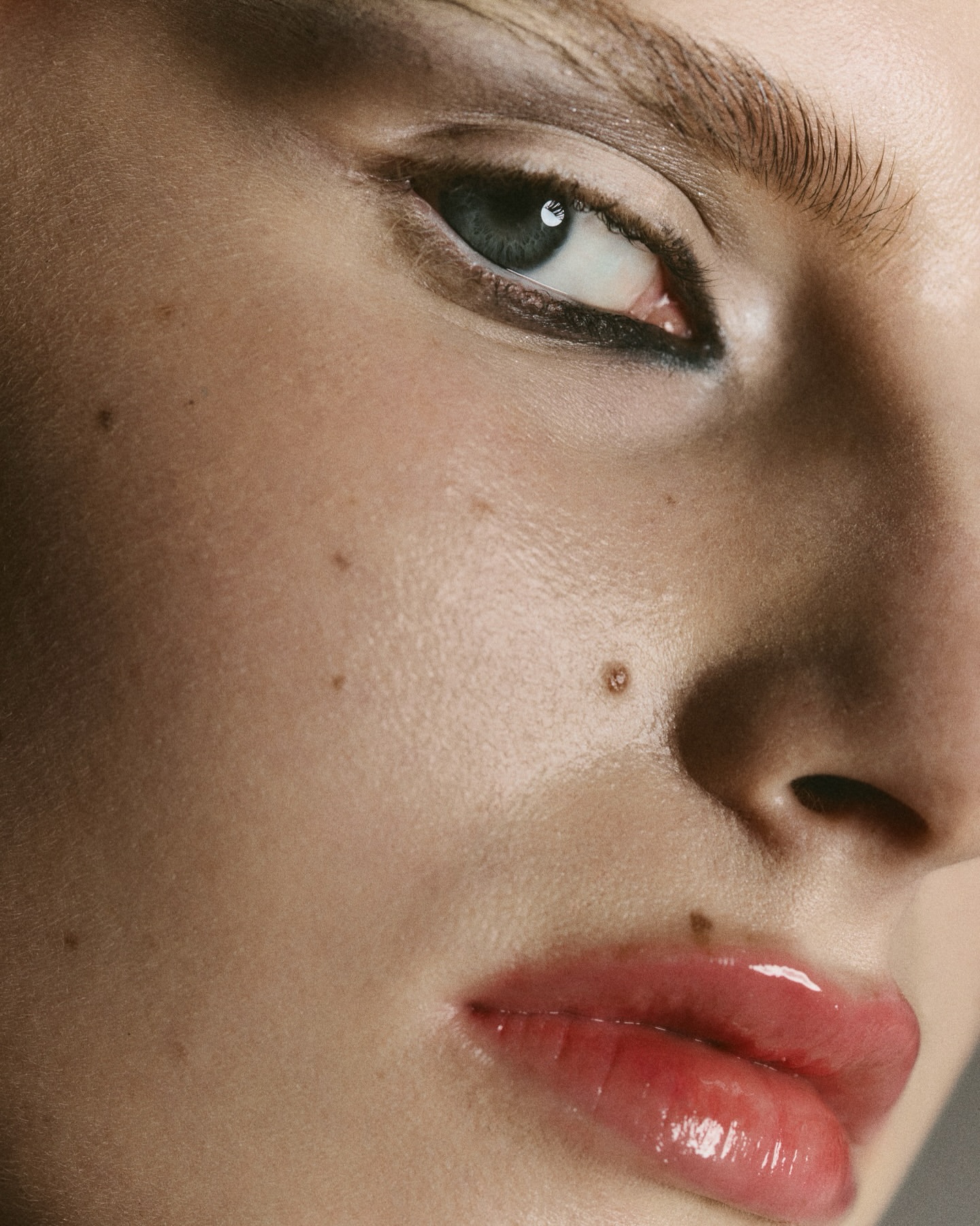 Close-up of a woman's face with light skin, detailed makeup, and a neutral expression, showcasing beauty and skincare features.