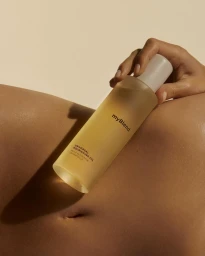 A hand holding a translucent bottle of MyBlend Universal Nourishing Oil against warm skin in Paris by Alice Jacquemin.