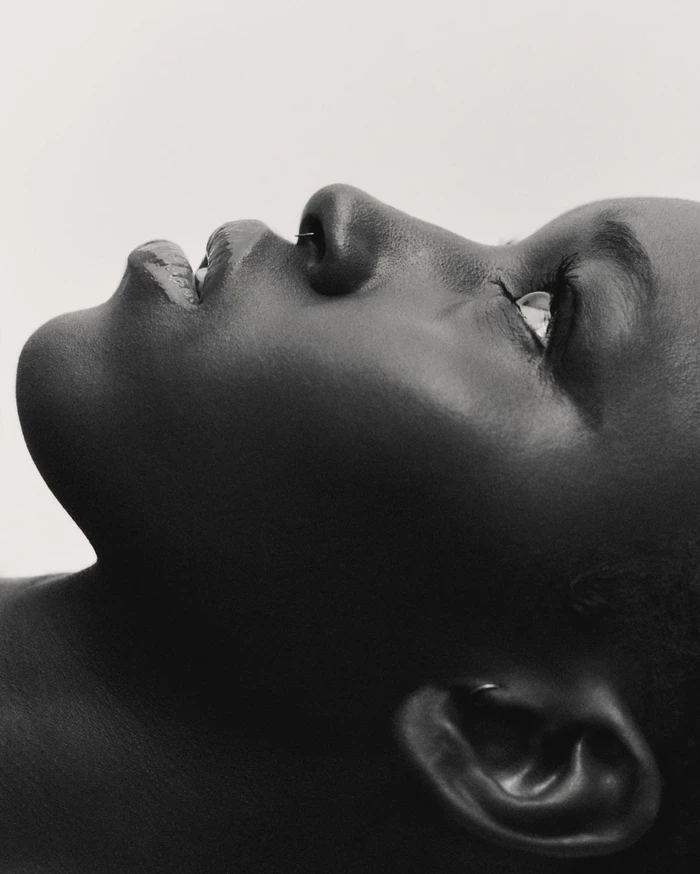 Profile portrait of a black woman in profile shot from below against a plain light background by Alice Jacquemin in Paris.