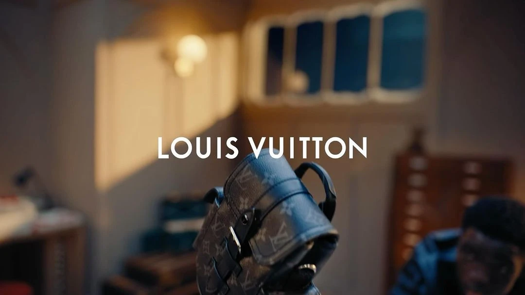 Luxury Louis Vuitton backpack with a signature logo pattern and leather trim, displayed in a softly lit studio with a blurred figure.