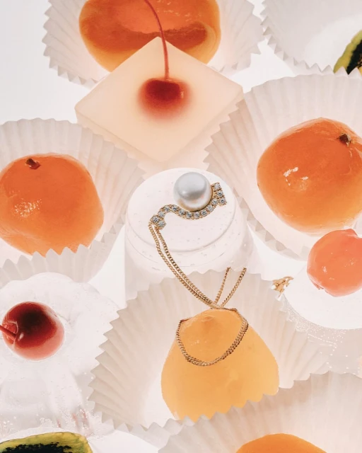Pearl necklace artfully displayed atop glazed fruit candies in cupcake liners. Sweet, edible jewelry concept. 