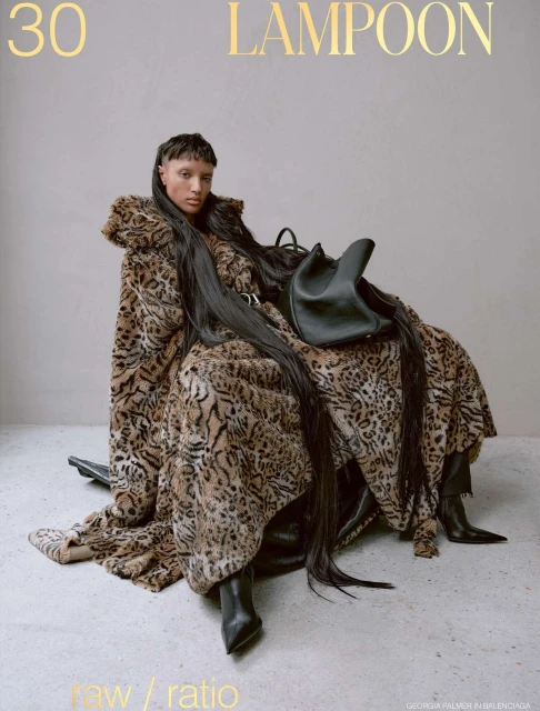 Fashion editorial featuring a woman draped in a leopard-print garment, seated with a black leather handbag, showcasing edgy style.
