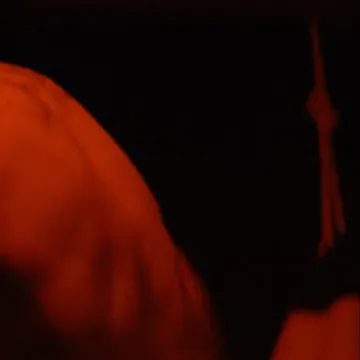 Close-up abstract shot of a person lit with intense orange light against a dark background