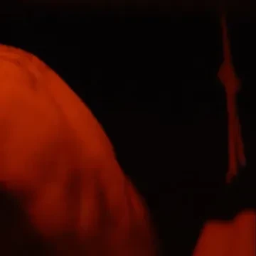 Close-up abstract shot of a person lit with intense orange light against a dark background