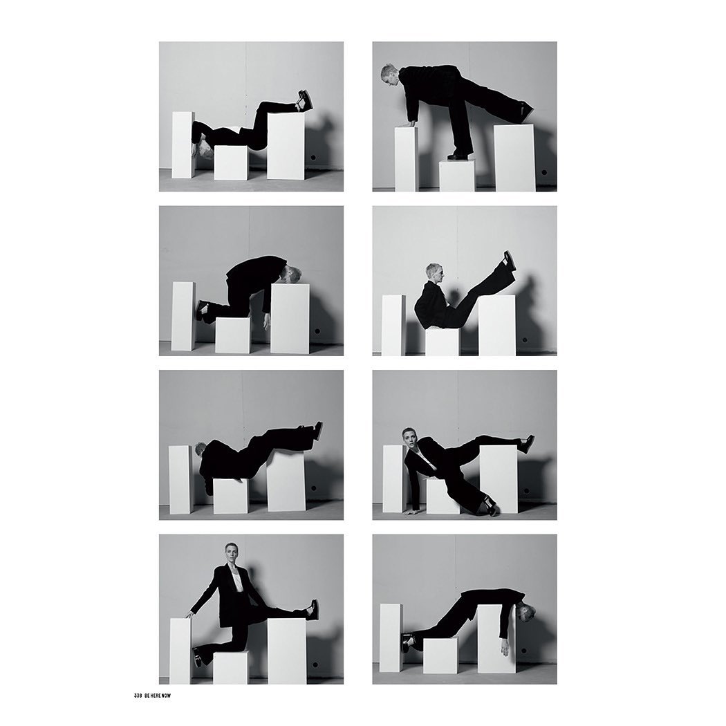 Black and white fashion shot shows woman in black suit posing in eight poses atop white cubic blocks against a plain light gray backdrop.