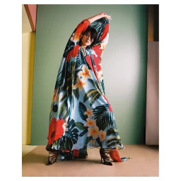 Model in a long floral print kaftan dress with arms raised against a green and cream studio backdrop by Alice Rosati