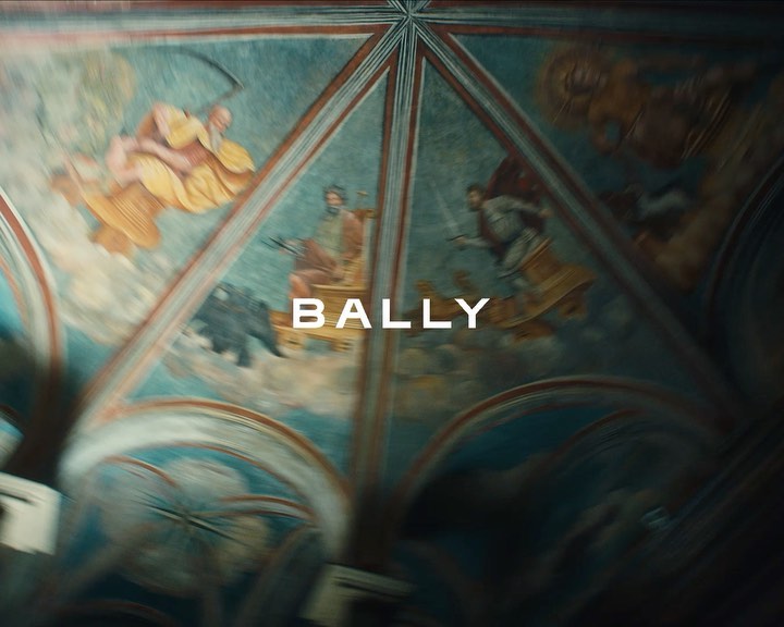 Painted ceiling with figures in yellow and white robes, and the BALLY brand name displayed in front of the artwork.