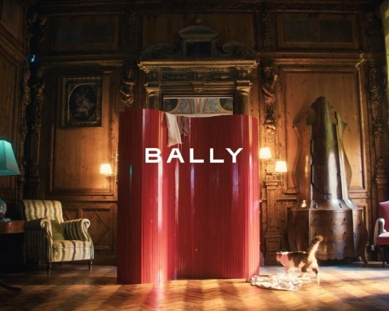 Ornate interior with 'BALLY' text on a modern red structure, featuring a cat, lamp, striped chair, and wooden parquet flooring.