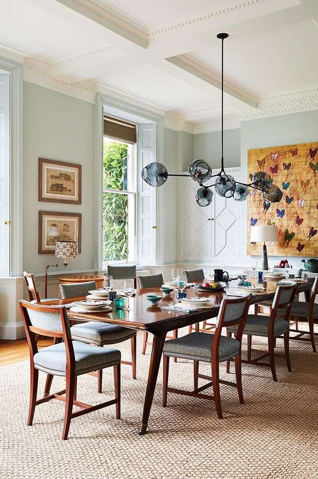 Formal dining room featuring a dark wood table with place settings, surrounded by upholstered chairs, modern pendant light, and artwork.