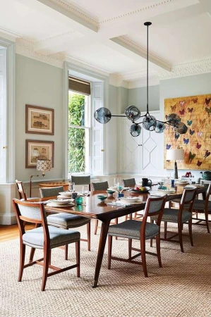 Formal dining room featuring a dark wood table with place settings, surrounded by upholstered chairs, modern pendant light, and artwork.