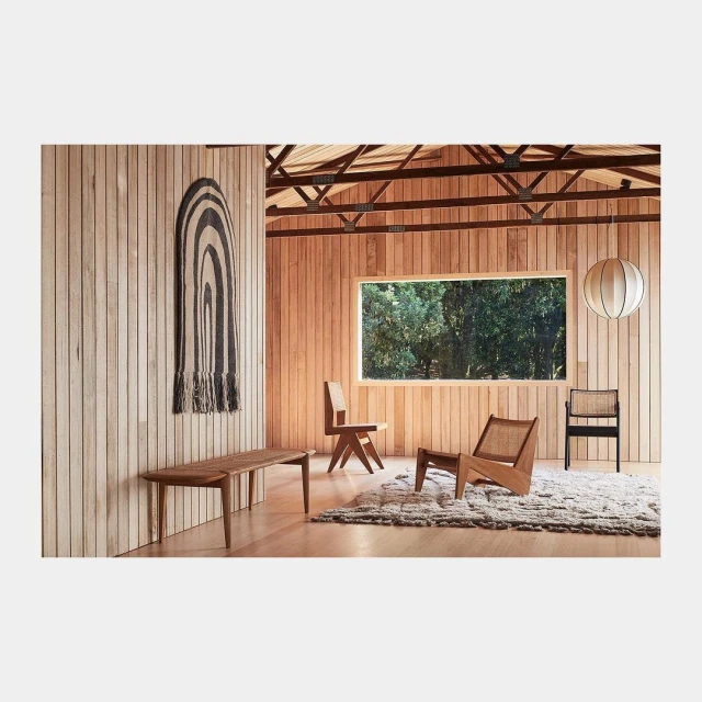 Interior view features wooden paneled walls, bench, chairs, rug, window with nature view, and hanging paper lantern.