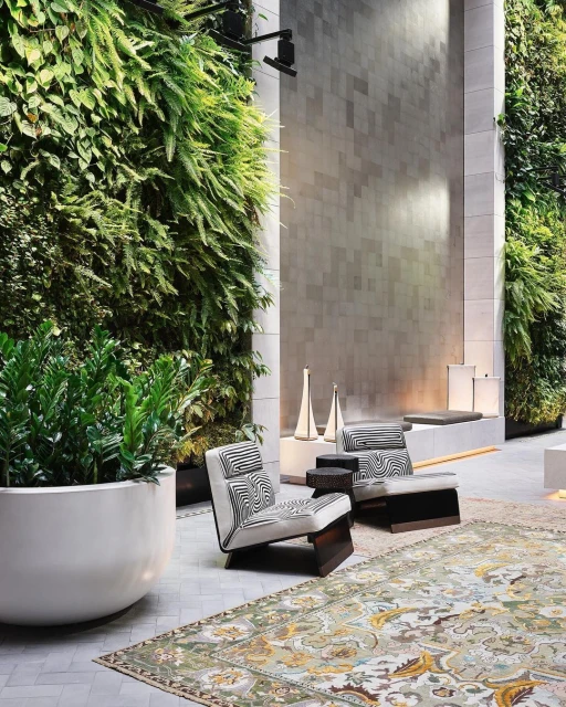 Indoor lounge area with two modern armchairs, a decorative rug, and a lush vertical garden wall creating a serene and stylish setting.