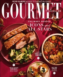 Overhead food photography of roasted pork belly, confit garlic, and potato dishes on a red tablecloth for a magazine cover