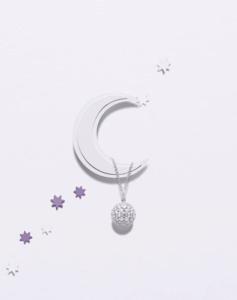 Elegant pendant necklace with a sparkling round diamond and set on a white surface with moon and star accents for luxury jewelry advertising.