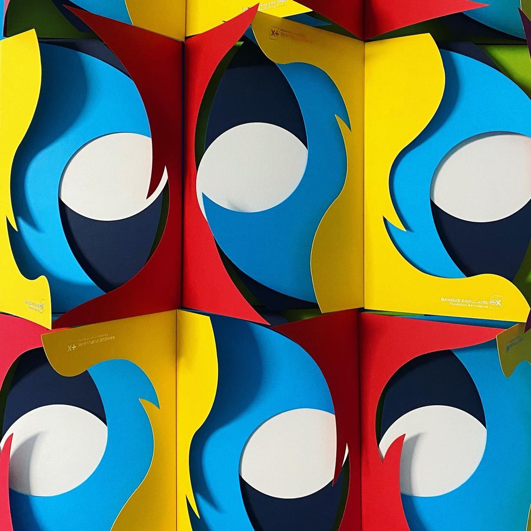 Abstract geometric art with vibrant colors: red, yellow, blue, and white, creating an eye-catching optical illusion pattern.