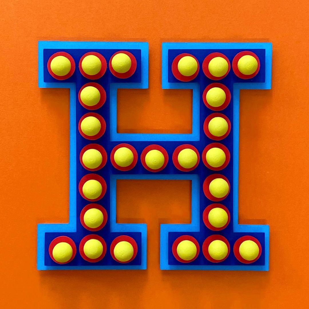 Stylized letter H with yellow circles in red rings and blue outline, against an orange background. Retro-inspired design, flat lay.