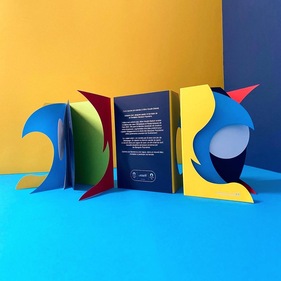 Abstract book display with colorful paper cutouts on a two-tone blue and yellow background for an eye-catching artistic arrangement.