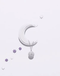 Silver crescent moon cut-out with a dangling diamond pendant necklace and small scattered star decorations on a light background