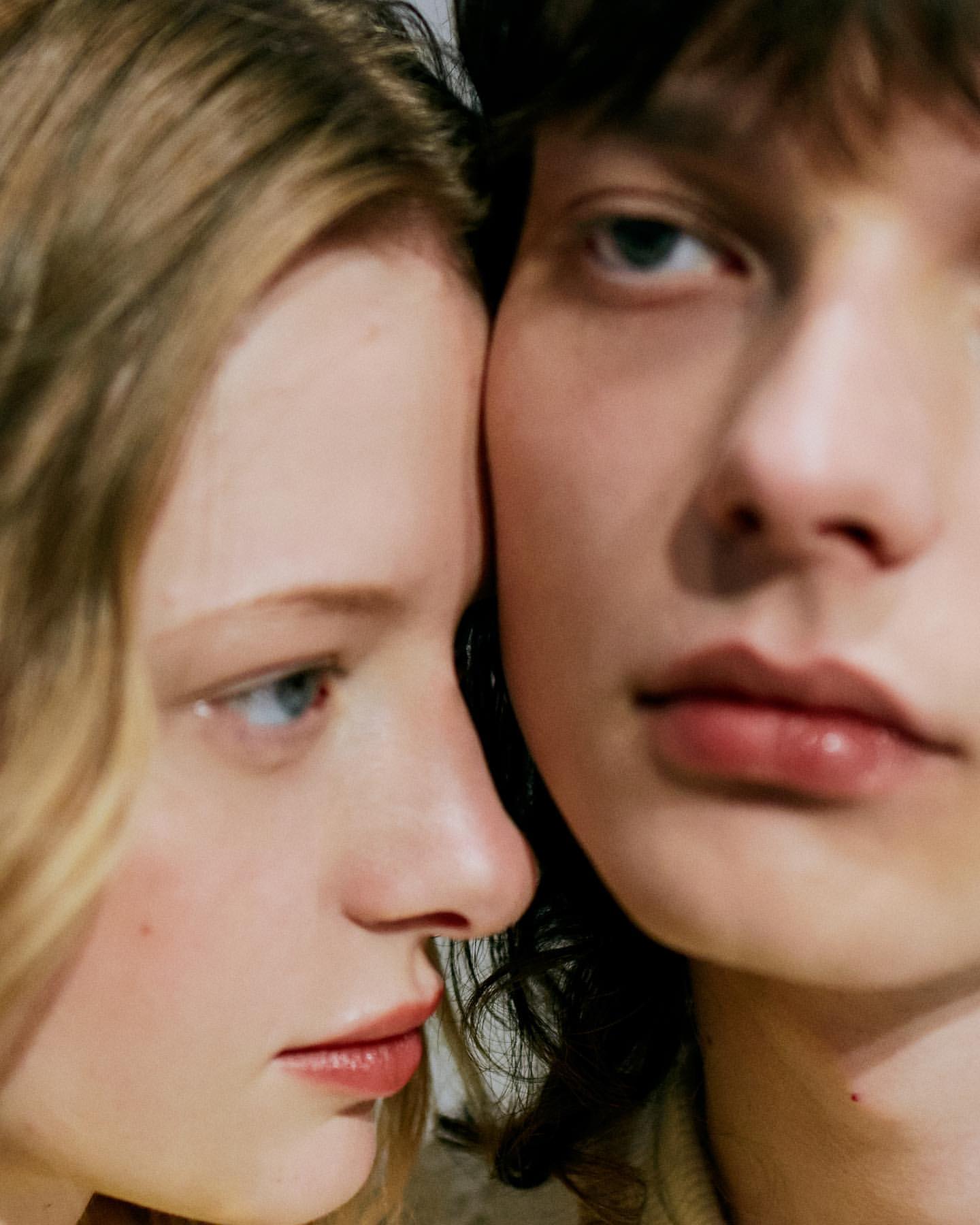 Close-up portrait featuring two young adult models with fair skin, close together, showcasing natural makeup and contemporary hair styles.