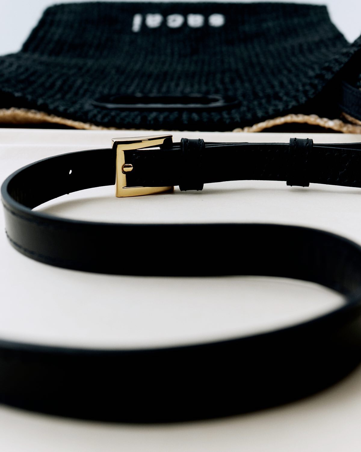 Close-up studio shot showcases a black leather belt with a gold buckle against a white backdrop, subtly highlighting the fashion accessory.