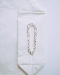 A silver link necklace displayed vertically on folded white paper packaging against a white background.