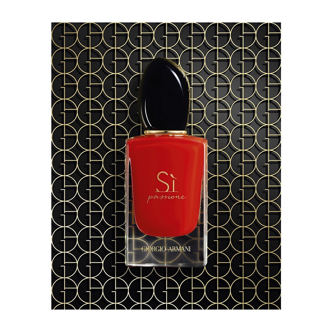 Elegant Giorgio Armani Si Passione perfume bottle on a reflective surface, against a geometric patterned backdrop. Beauty and luxury.