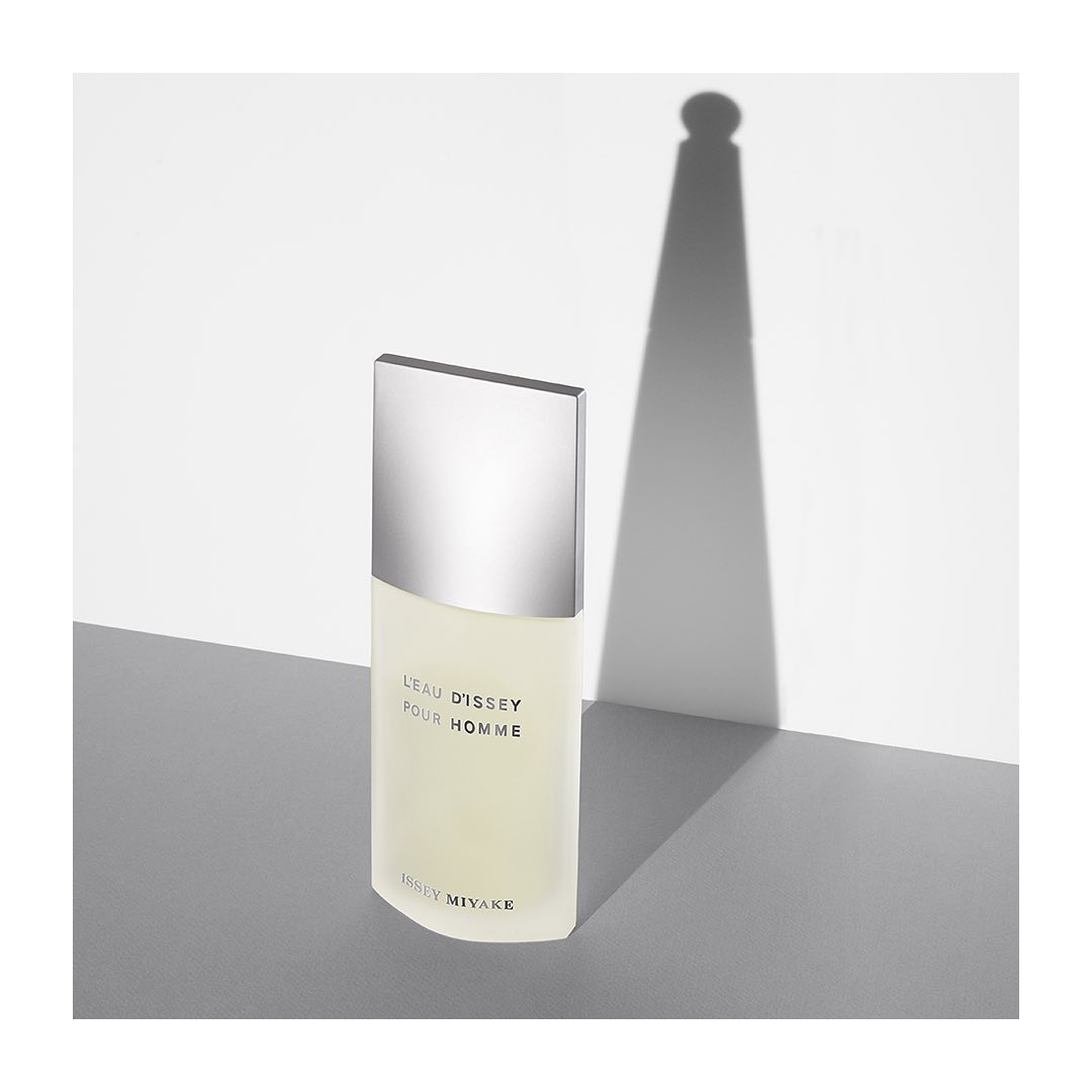 Issey Miyake L'Eau D'Issey Pour Homme bottle on a light gray surface with a shadow, showcased in a minimalist studio setting.