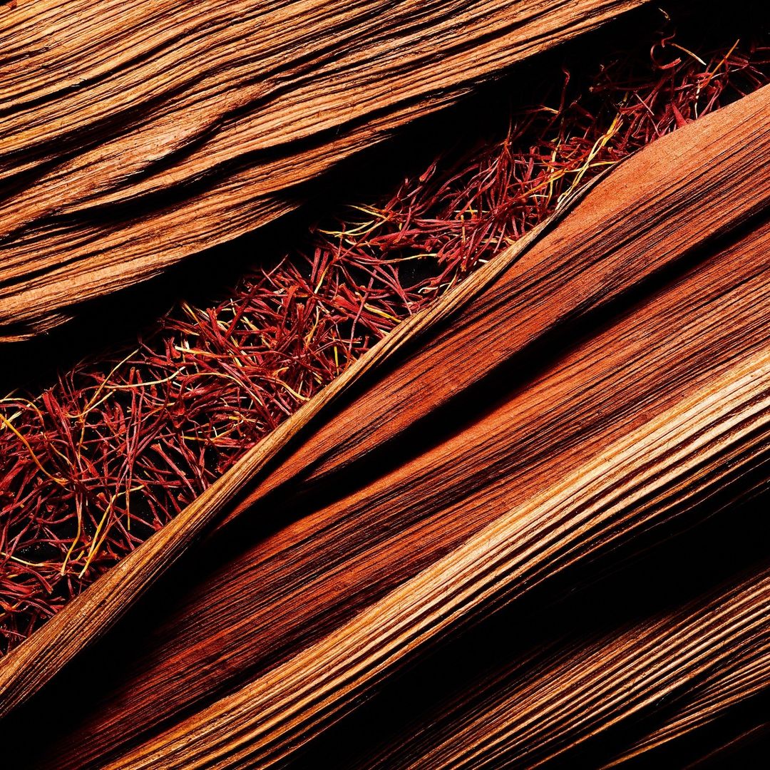 Close-up abstract of dried palm leaves with linear texture, earthy tones, and dark shadows creating a natural, organic pattern.