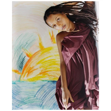 Portrait of a Black woman with long braided hair wearing a plum draped dress against a colourful hand-drawn pastel backdrop.