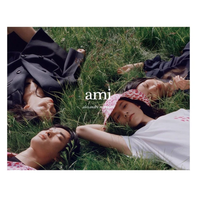 Four young adults rest on lush green grass outdoors, posing for a fashion editorial, showcasing youthful style and natural setting.