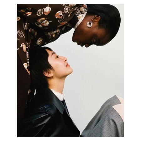 Two female models posing closely together against a white background, captured in a portrait by Allyssa Heuze.