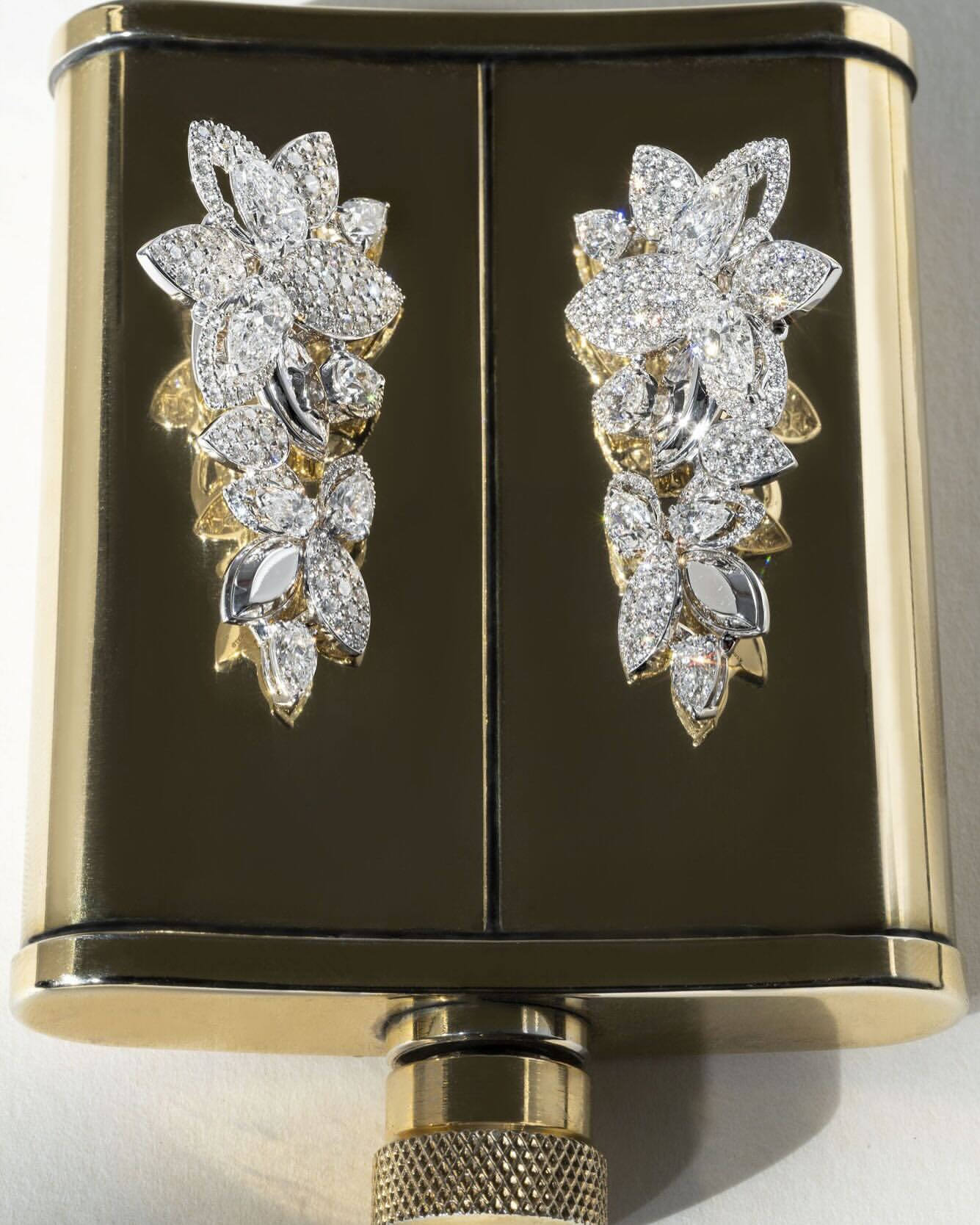 Close-up of an ornate gold and black hip flask with diamond flower decorations, showcasing luxury and intricate design.