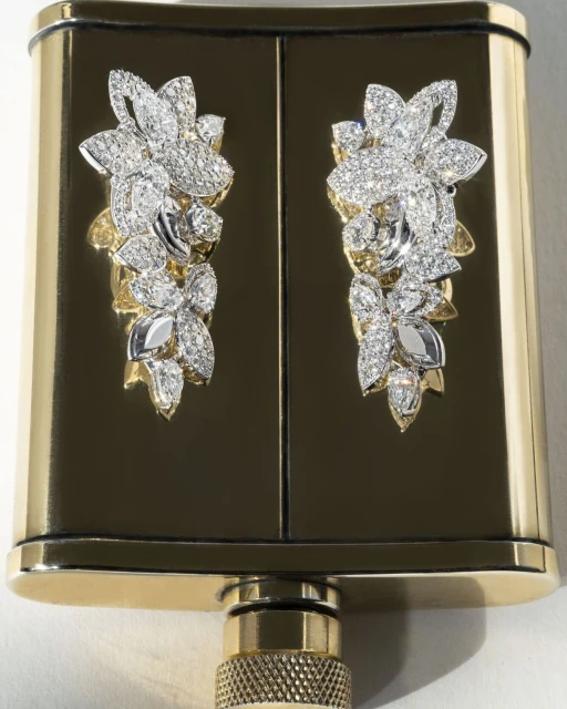 Close-up of an ornate gold and black hip flask with diamond flower decorations, showcasing luxury and intricate design.