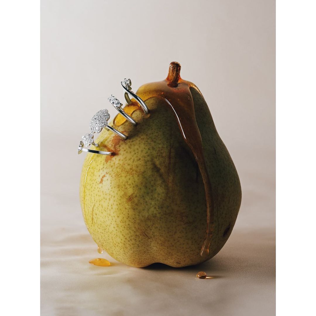 Pear with jewelry and honey: a close-up still life featuring a fresh pear adorned with rings and drizzled with dripping honey.