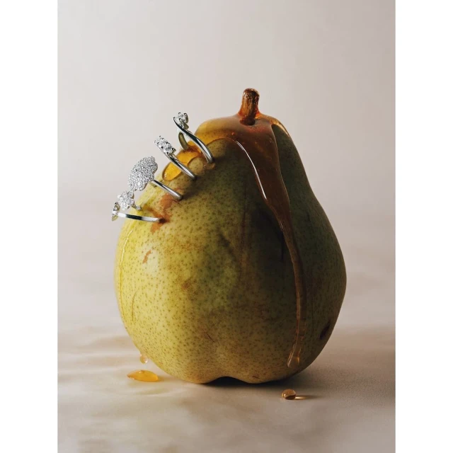 Pear with jewelry and honey: a close-up still life featuring a fresh pear adorned with rings and drizzled with dripping honey.