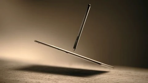 Product shot of a floating stylus pen and tablet against a mottled, graduated tan background with visible shadows and metallic sheen.