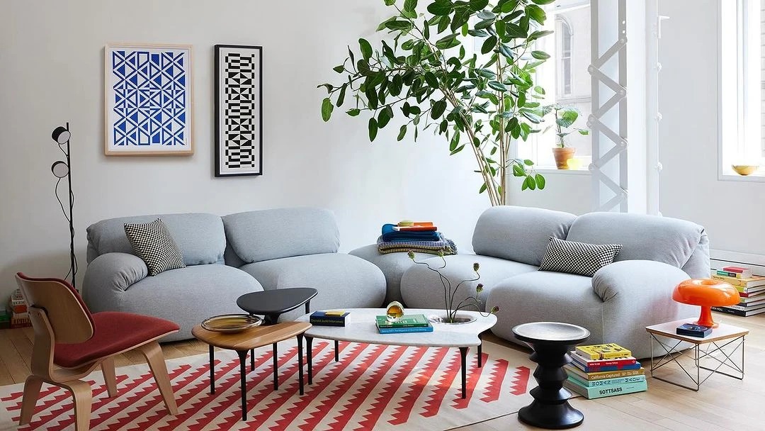 Living room interior featuring a grey sofa, patterned rug, and various decor elements, with a bright and airy ambiance.